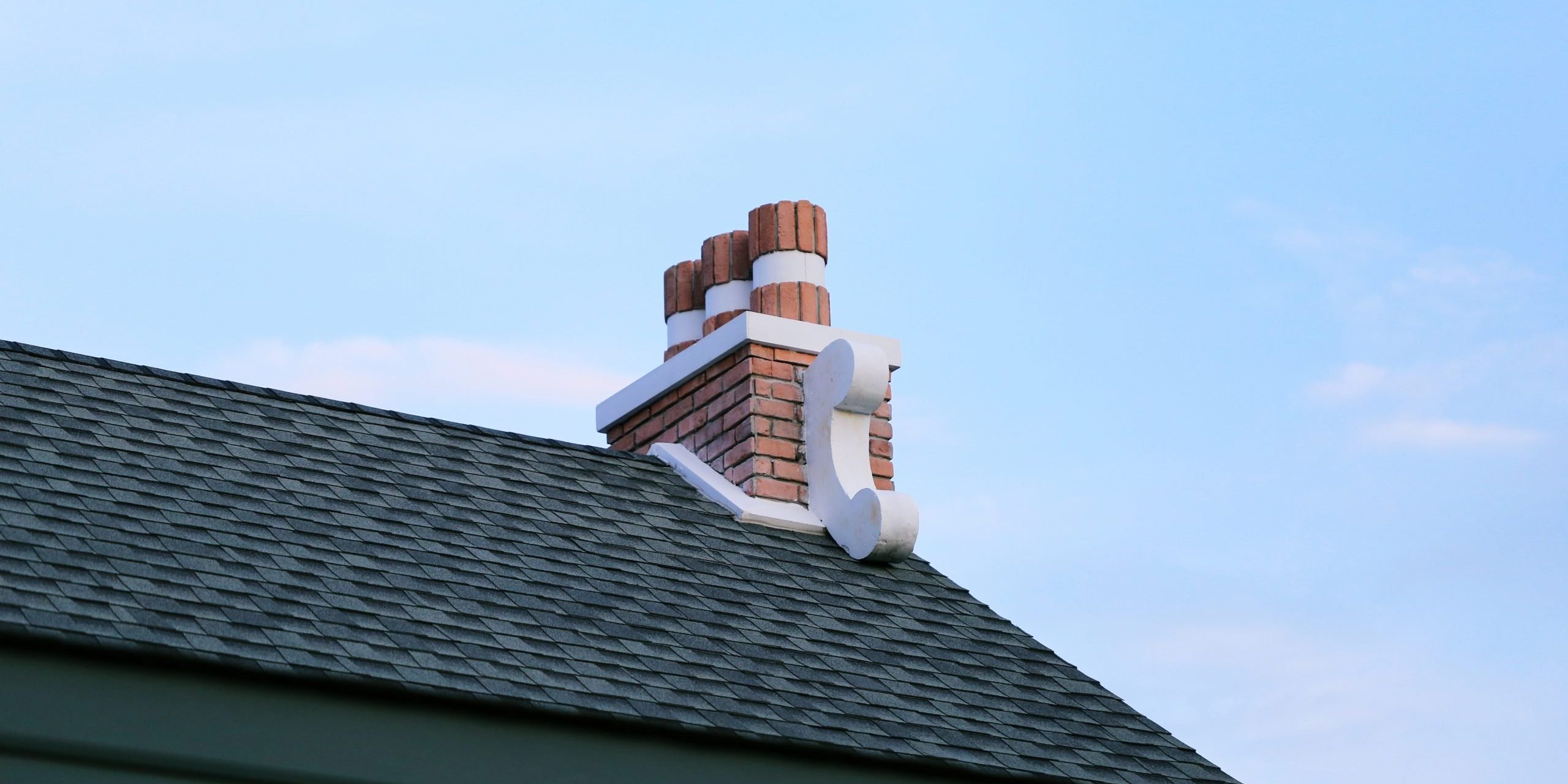 chimney-on-house-roof-closeup-blue-sky-background